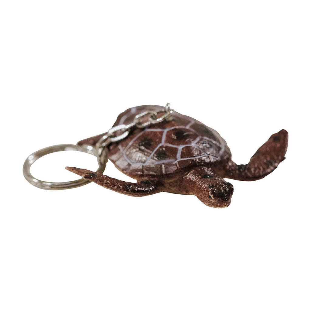 A brown keychain in the shape of a green sea turtle with a metal ring attached.