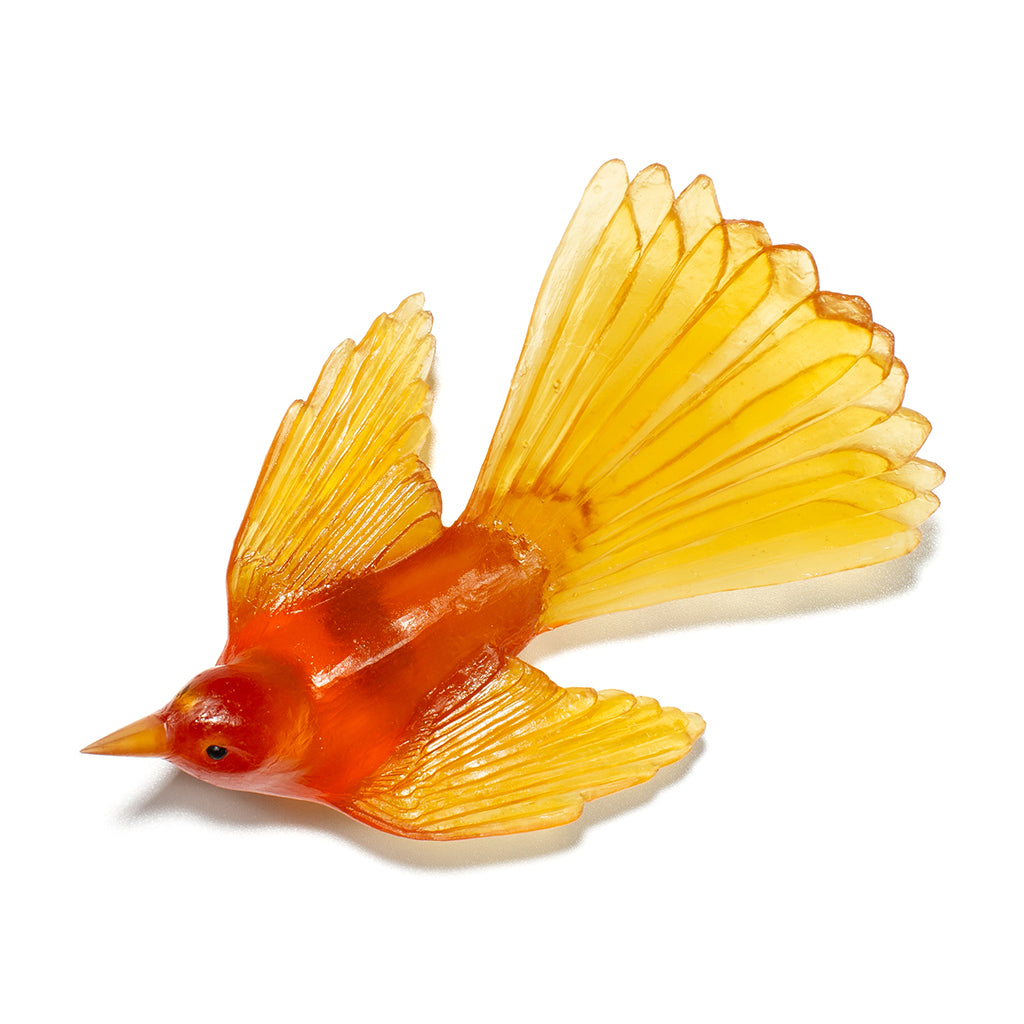 A translucent orange and yellow bird figurine with spread wings, photographed on a clean white background.