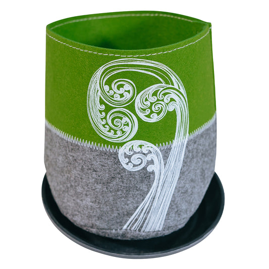 A green and grey Ecofelt grow bag with a New Zealand native flora print, accompanied by a saucer. The bag is made from recycled plastic bottles and the saucer is made from biodegradable plant fibre.