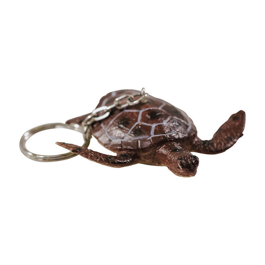 A brown keychain in the shape of a green sea turtle with a metal ring attached.