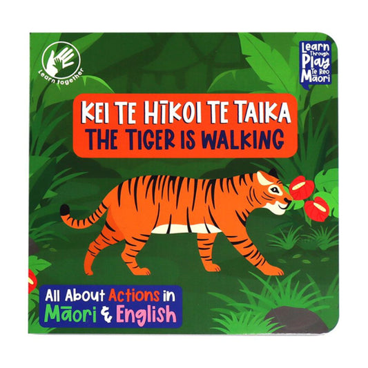 A children's board book titled 'Kei Te Hiko Te Taika: The Tiger Is Walking' with a colorful illustration of a tiger in a green jungle scene. The cover includes the 'learn together' logo and the 'Learn You Play in Mâori' logo.