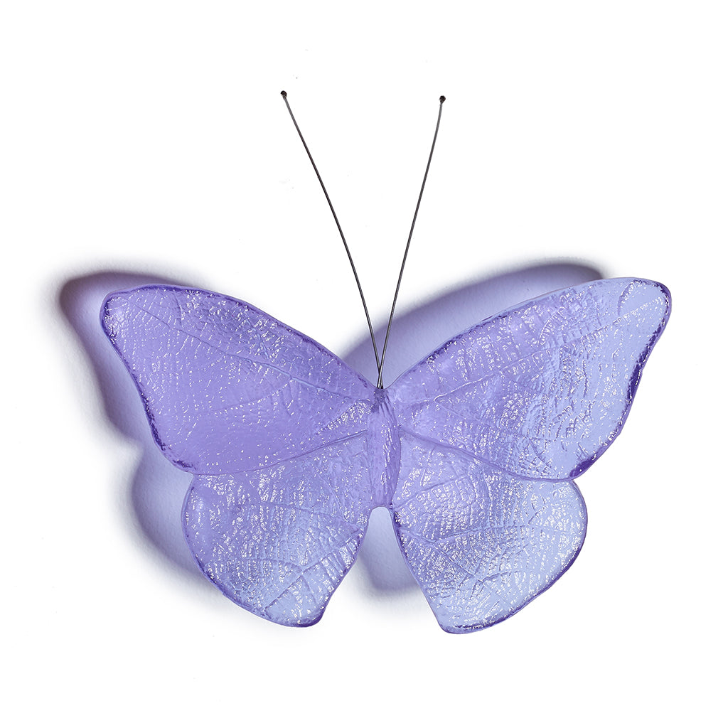 A single butterfly-shaped decorative object with translucent lavender-purple wings and thin dark antennae, shown on a plain white background with a soft shadow.