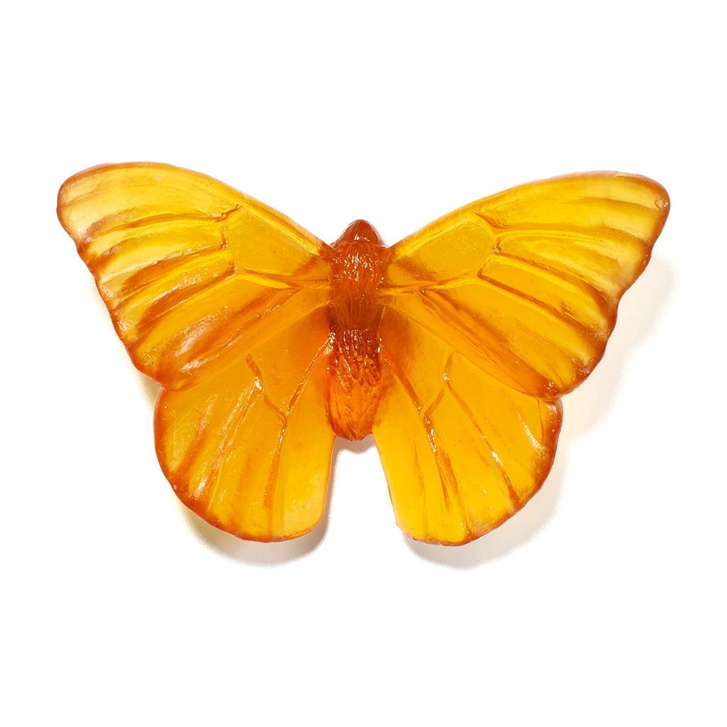 An orange butterfly-shaped glass sculpture with detailed wing patterns, displayed on a clean white background.