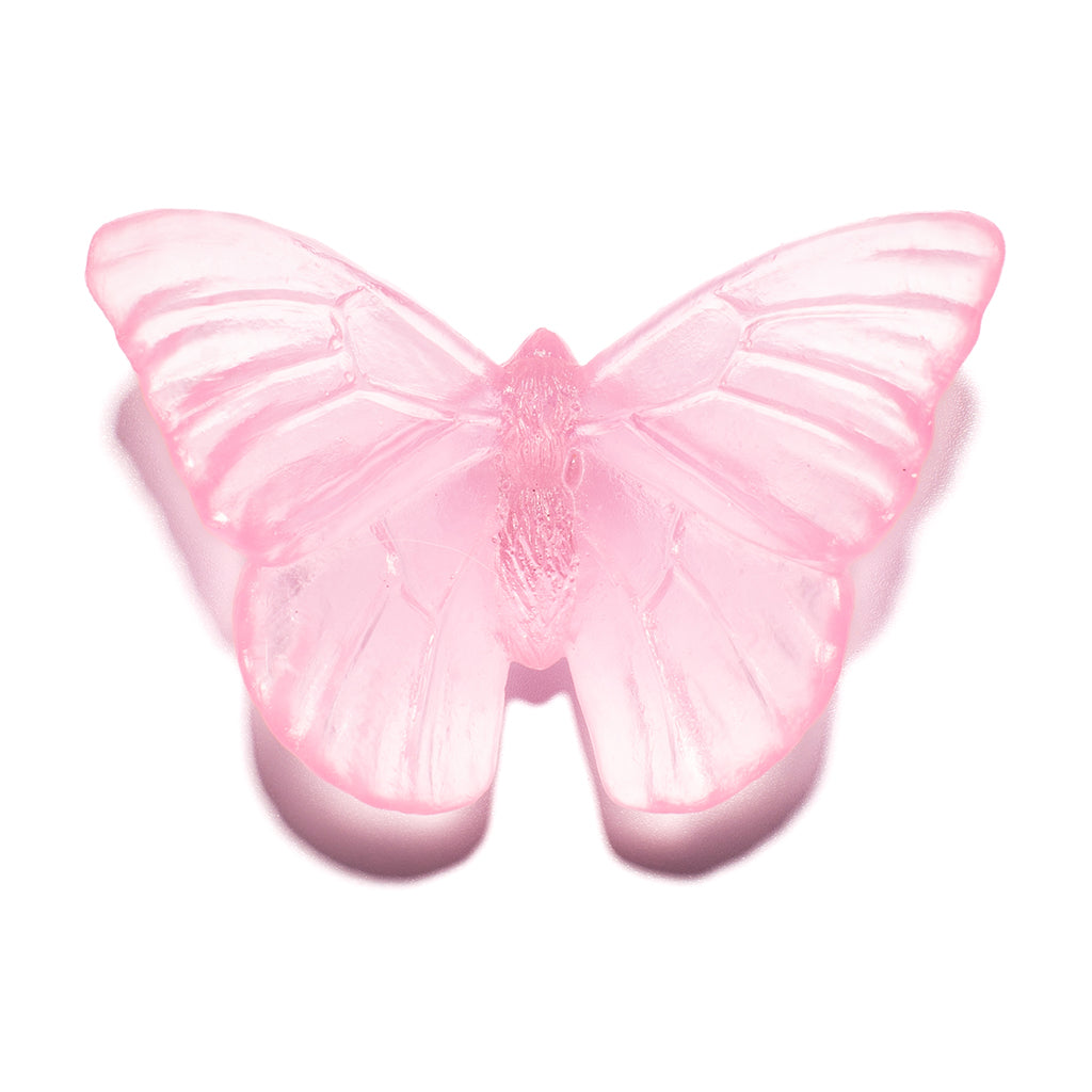A translucent pink butterfly-shaped glass sculpture, shown against a plain white background with a soft shadow.