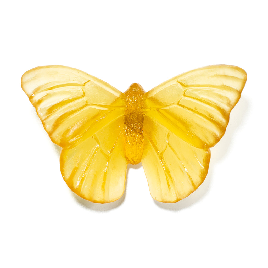 A translucent yellow butterfly-shaped glass sculpture with detailed wing patterns, displayed on a clean white background.