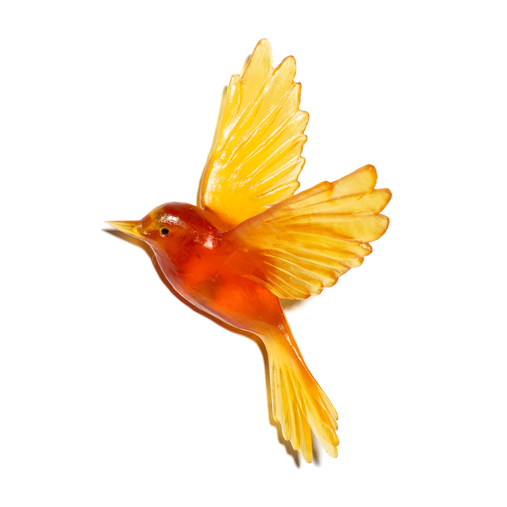 A translucent amber-orange bird figurine with yellow wings and tail, shown on a plain white background.