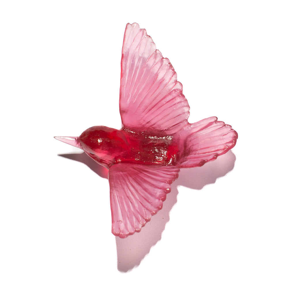 A translucent red glass bird figurine, shaped like a tomtit with wings spread, set against a plain white background with a soft shadow.