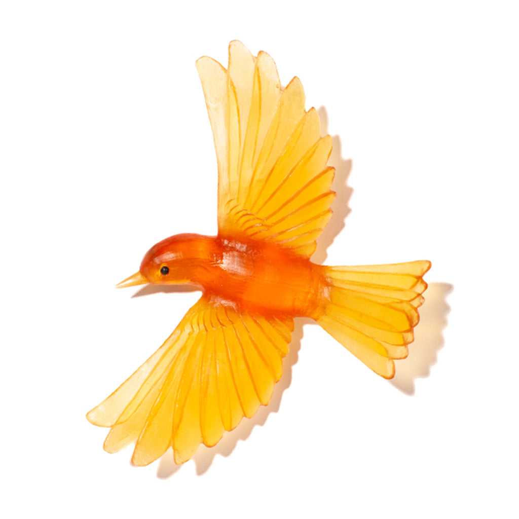 A small flying bird figurine or ornament in translucent orange and yellow, shown on a plain white background with a soft shadow.