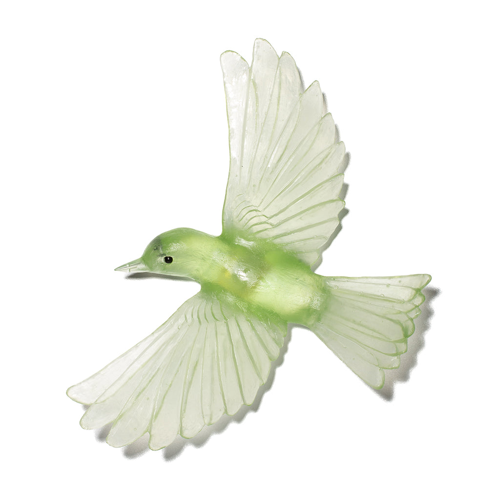 A pale green glass bird sculpture with wings outstretched in flight on a white background.