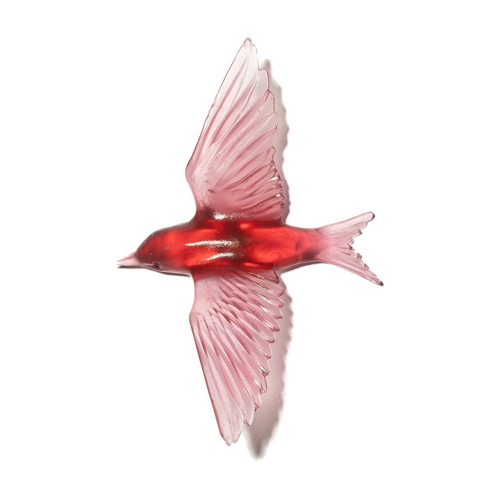 A red glass bird sculpture in graceful flight, on a white background