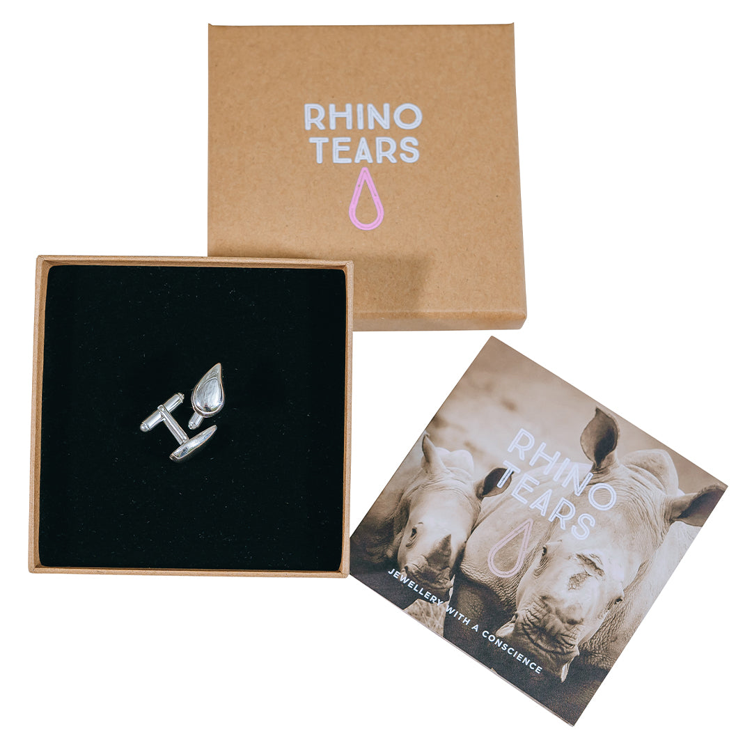 Rhino Tears silver cufflinks packaging, including a silver cufflink on a black background, with a cardboard box in the background and a tag with the brand name and logo.