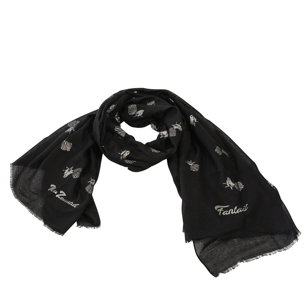 A black scarf with silver foil print depicting New Zealand's native piwakawaka (fantail) bird.