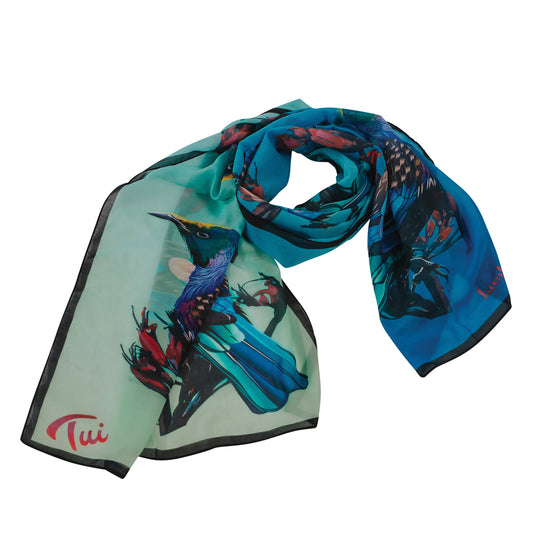 A lightweight scarf with a gradient of blue to black, featuring a colorful bird print, folded and displayed flat.